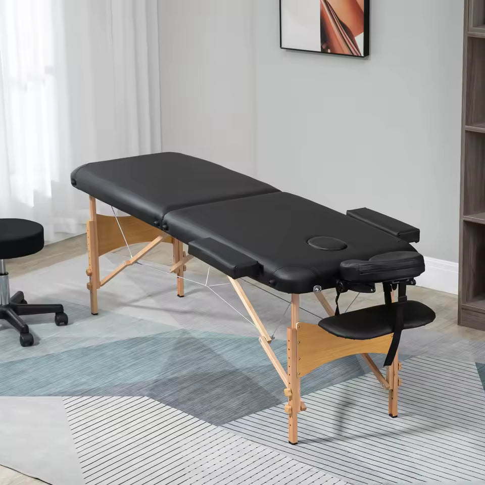 Table de massage pliante SKORTA noire installée dans une pièce lumineuse avec un tabouret de praticien