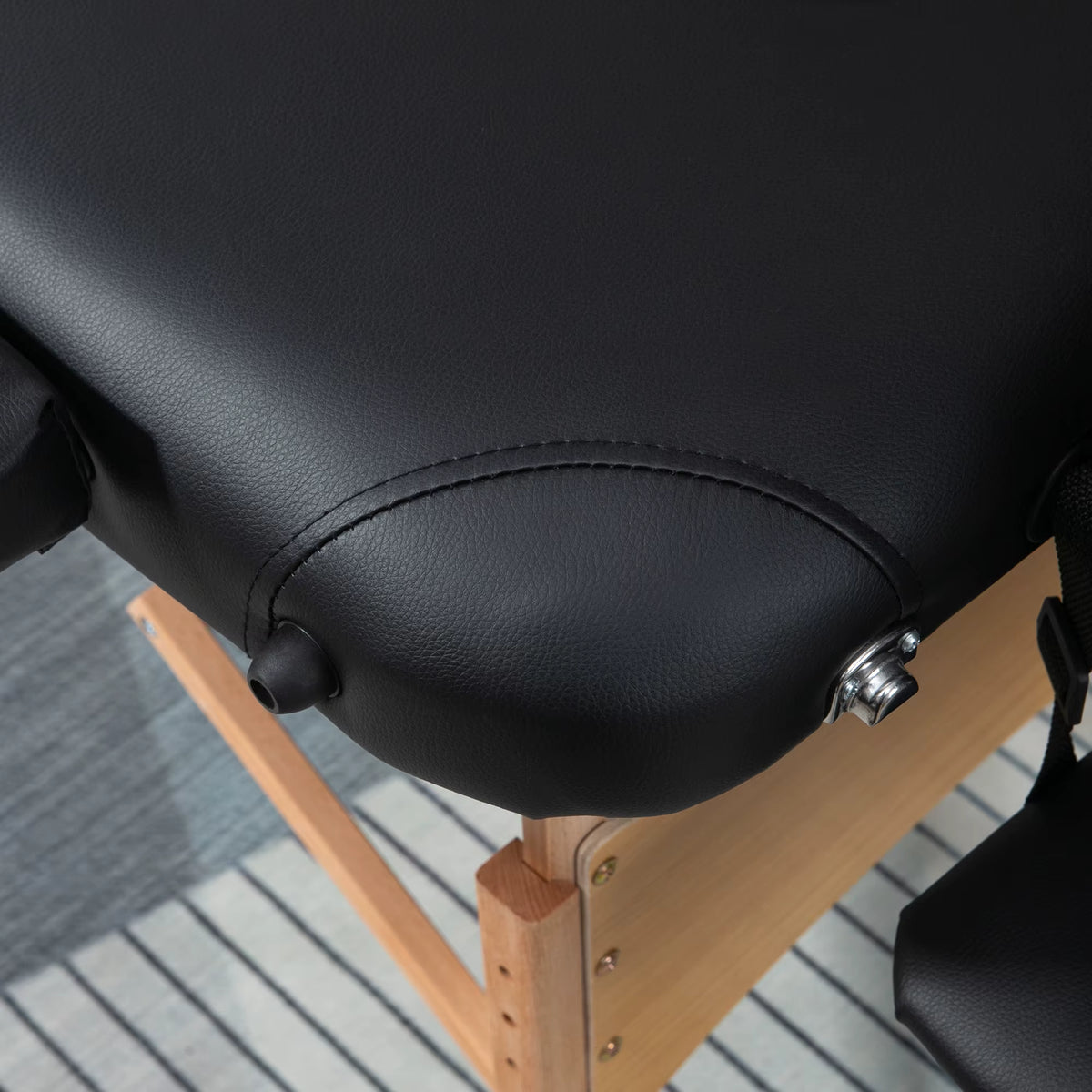 Gros plan sur l'assise en similicuir noir et la molette de réglage de la table de massage SKORTA