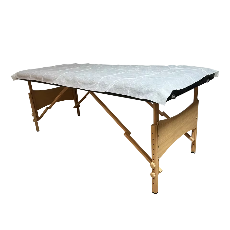 Drap de protection HORA posé sur une table de massage pliante en bois