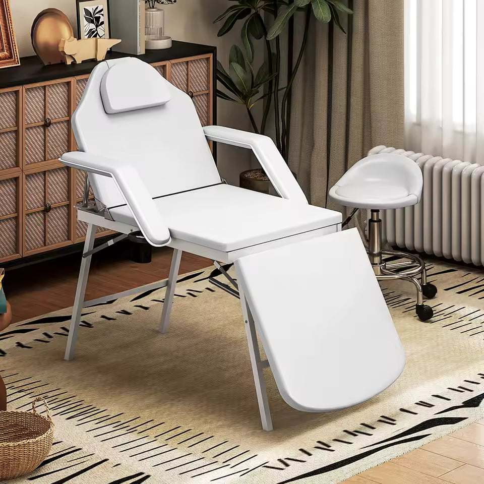Table de soin pliante WORTA blanche installée dans un intérieur avec un tabouret d'esthéticienne