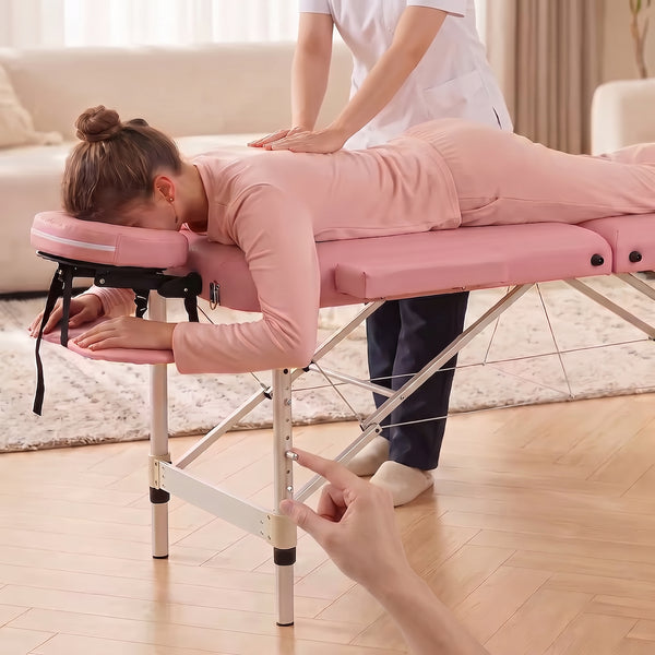 Praticienne massant une cliente sur la table pliante PIKKO rose, réglage de la hauteur des pieds